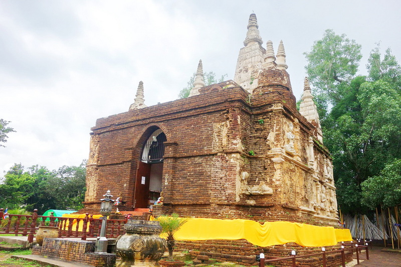 Ancient Brick Stupa at Wat Jed Yod Historic brick stupa with surrounding greenery and yellow cloth at the base at Wat Jed Yod.