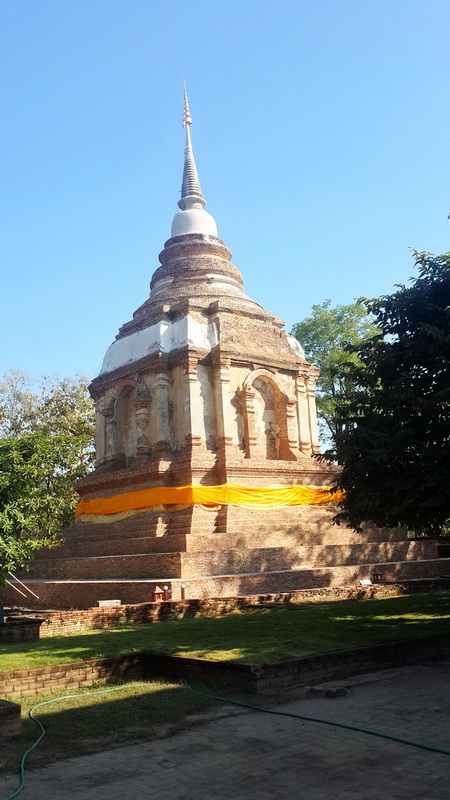Historic Stupa with Spire at Wat Jed Yod Ancient brick stupa with spire and orange cloth in greenery setting at Wat Jed Yod.