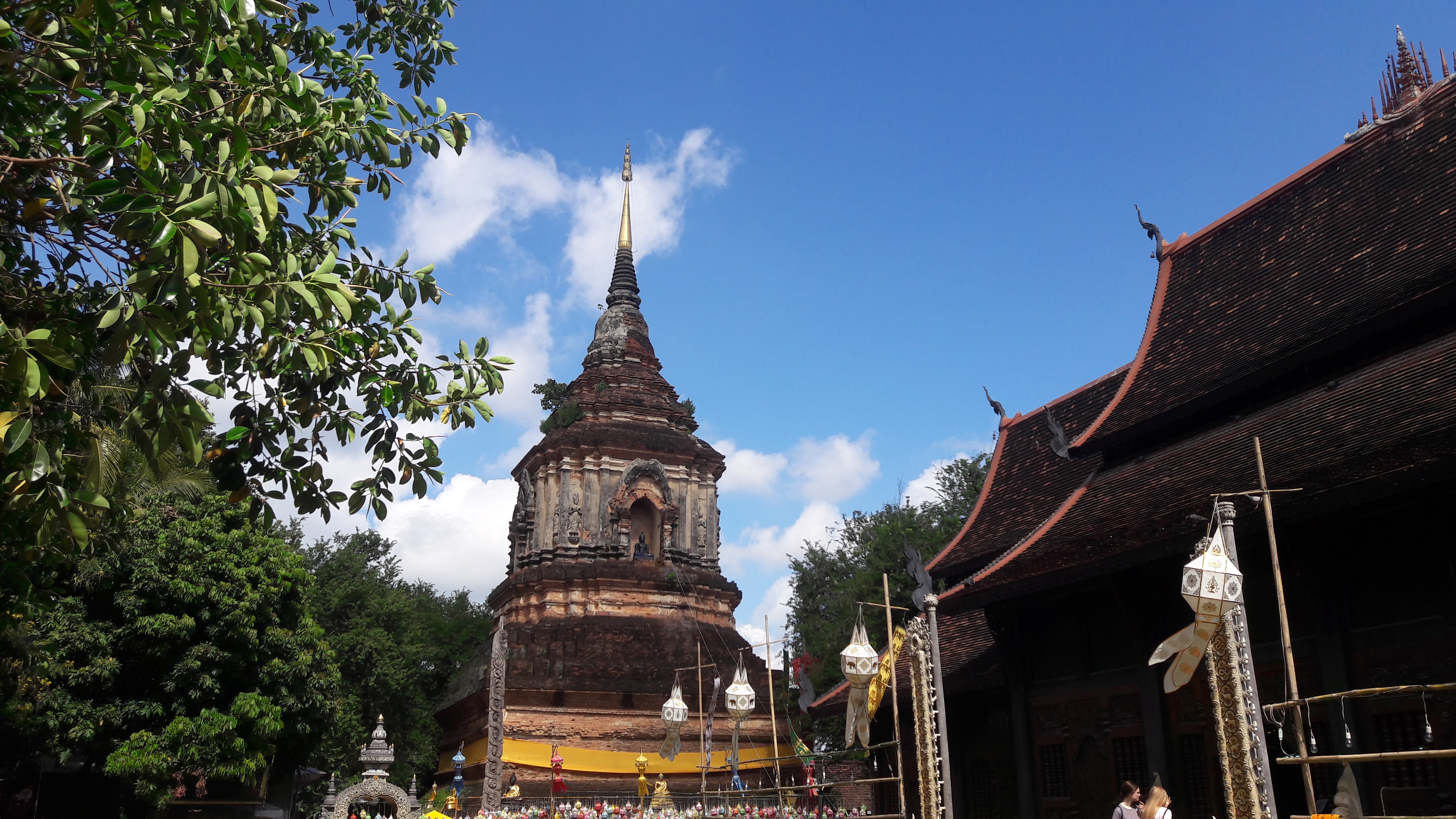 Ancient brick pagoda with surrounding trees and a clear sky above at Wat Lok Moli.