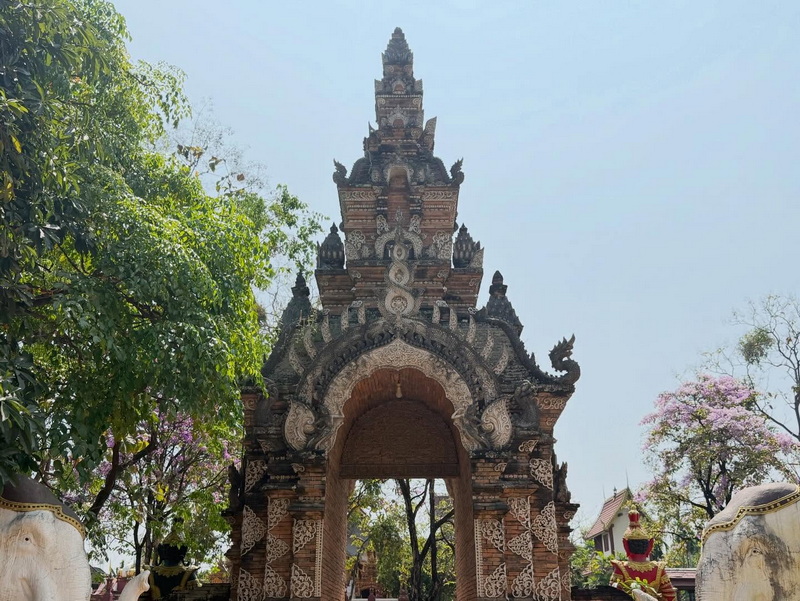 Temple Gate with Carvings at Wat Lok Moli Tall, decorative temple gate with carvings and dragon sculpture among trees at Wat Lok Moli.