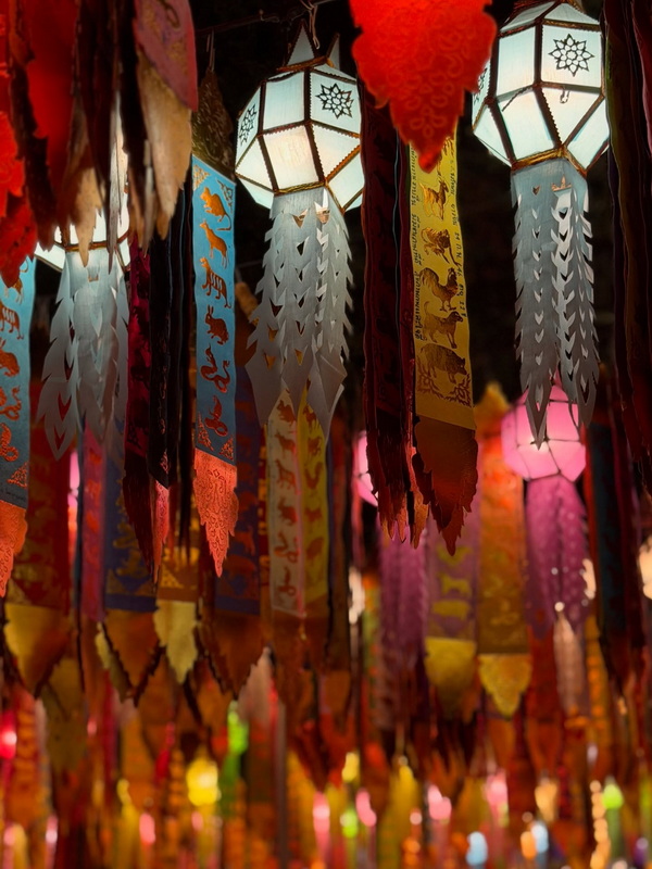 Colorful lanterns with paper decorations hanging indoors during a festival at Wat Lok Moli.