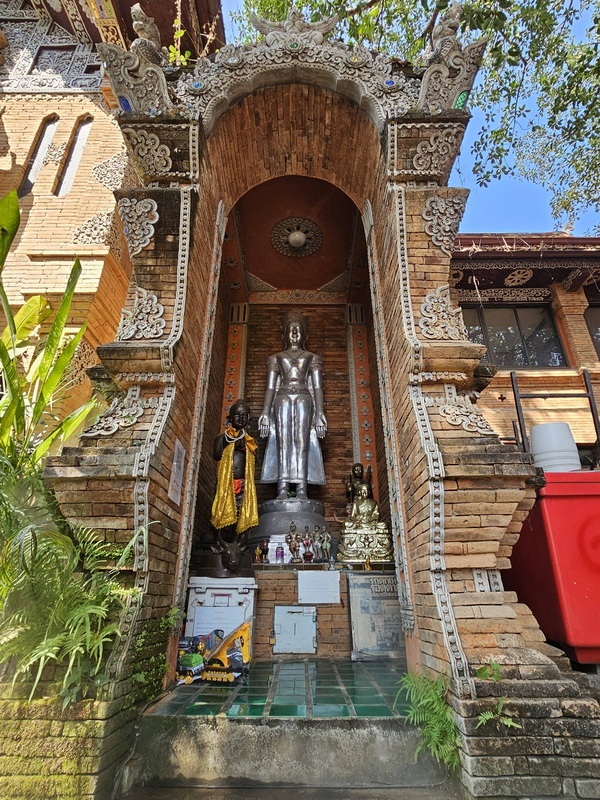 Decorative Brick Archway with Statues at Wat Lok Moli Brick archway with ornate white details and statues inside, sunlight bright at Wat Lok Moli.