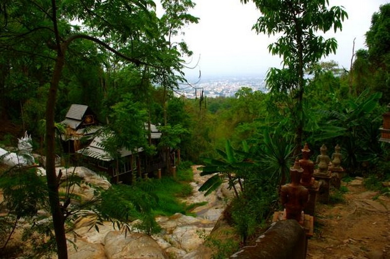 Forest Pathway with Steps at Pha Lad Temple Forest trail with steps, trees, and small structures amid greenery at Pha Lad Temple.