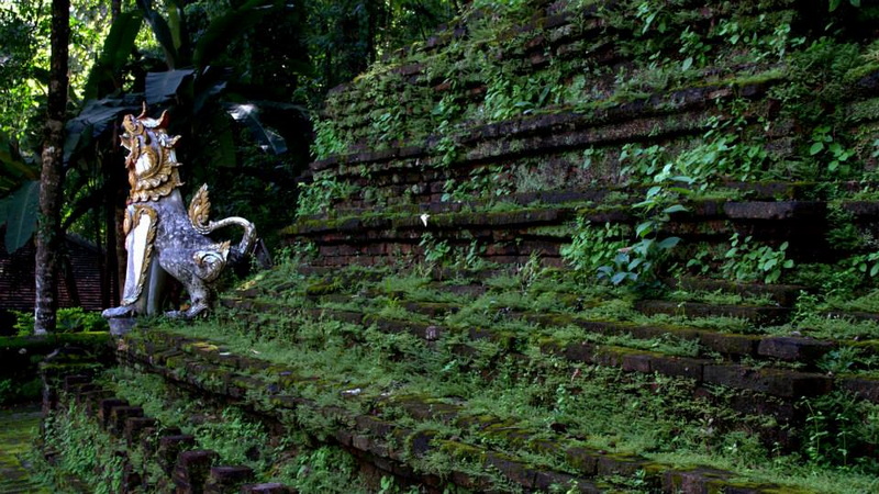 Mythical Creature Statue in Lush Garden at Pha Lad Temple Statue of a mythical creature among moss-covered brick steps in lush greenery at Pha Lad Temple.