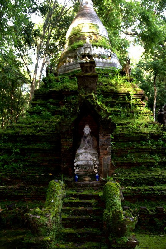 Mossy Shrine Among Trees at Pha Lad Temple Stone shrine with a statue nestled among mossy steps and green trees at Pha Lad Temple.