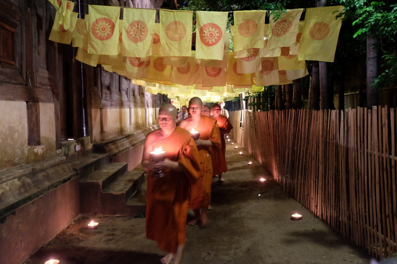 Monks with Candles During Ceremony at Wat Phan Tao Monks carrying candles walking under decorated flags at night at Wat Phan Tao.