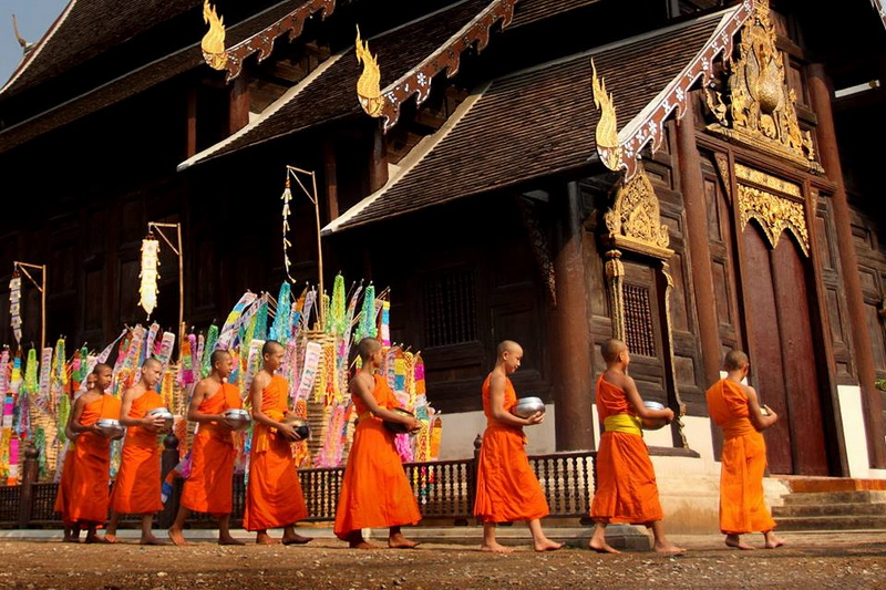 Monks Walking by Temple at Wat Phan Tao Young monks in orange robes walking in front of a wooden temple with gold accents at Wat Phan Tao.
