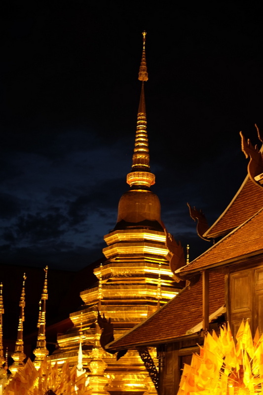 Illuminated Golden Stupa at Night at Wat Phan Tao A golden tiered stupa lit up at night with wooden temple structures nearby at Wat Phan Tao.