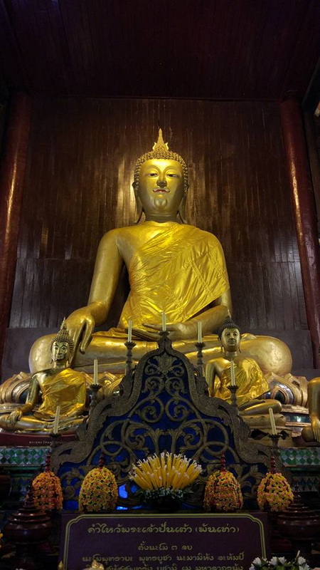 Golden Buddha in Temple at Wat Phan Tao Gold Buddha statue with smaller statues and floral offerings inside a temple at Wat Phan Tao.