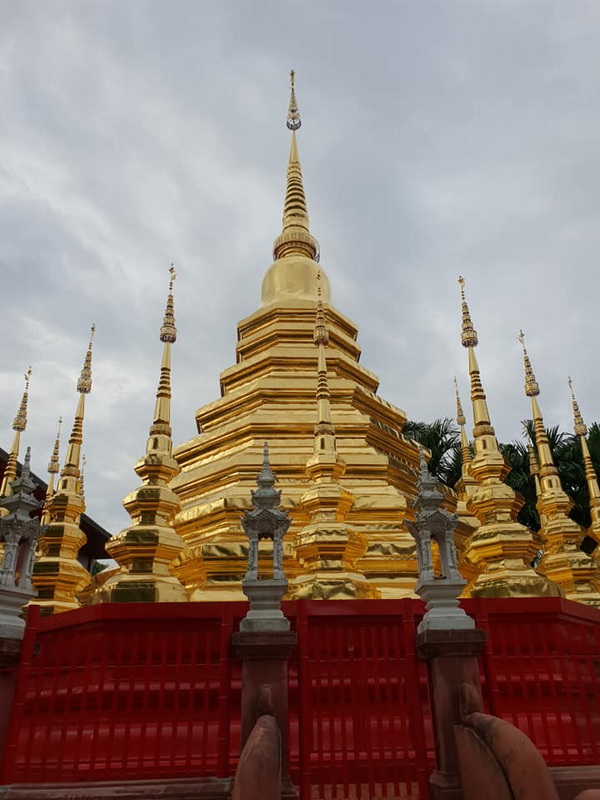 Golden Stupa with Spires at Wat Phan Tao Large golden stupa with smaller surrounding spires against a cloudy sky at Wat Phan Tao.