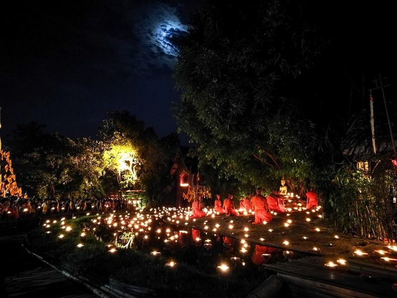 Night Ceremony with Candles at Wat Phan Tao Monks in red robes sitting on a platform with candles under a moonlit sky at Wat Phan Tao.