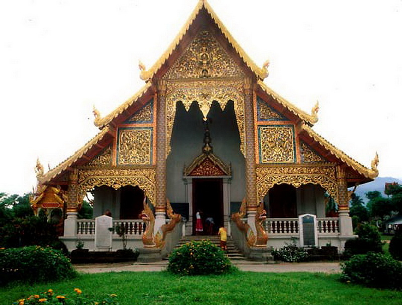 Thai Temple Architecture at Wat Phra Singh Traditional Thai temple with ornate gold decorations and a multi-tiered roof amidst greenery at Wat Phra Singh.