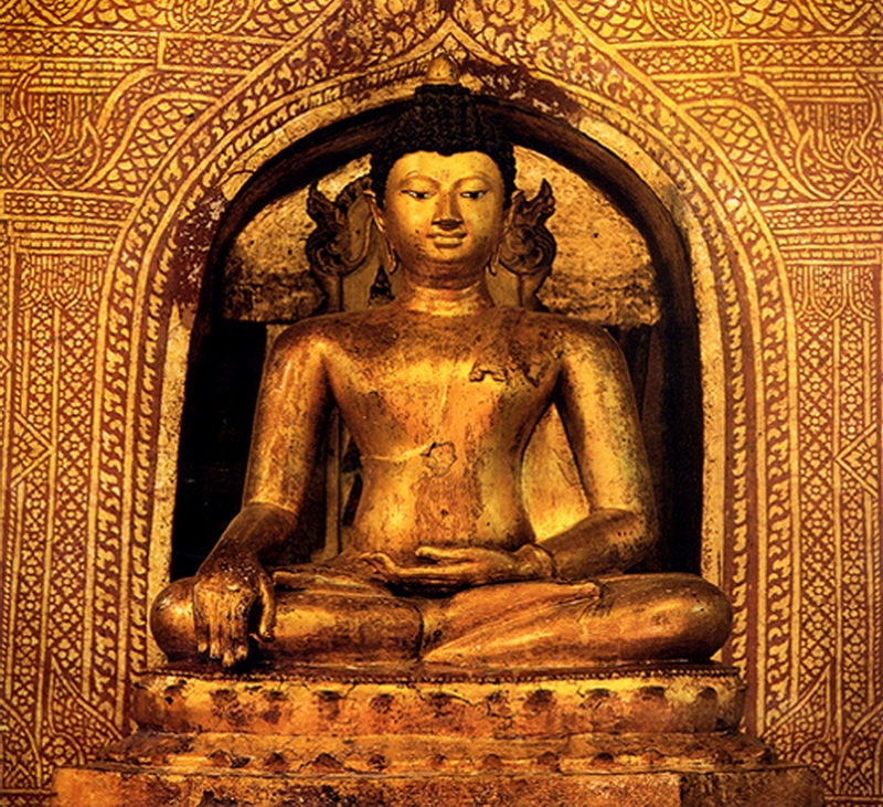 Golden Buddha in Temple at Wat Phra Singh Golden Buddha statue seated with detailed patterns on the wall behind it inside a temple at Wat Phra Singh.