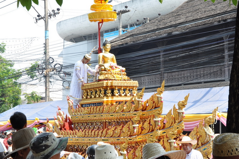 Buddha Parade Celebration at Wat Phra Singh Golden Buddha statue on a decorated float during a cultural parade with spectators watching at Wat Phra Singh.