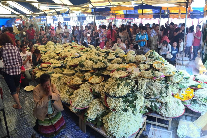 Flower Display at Festival at Wat Phra That Doi Kham People gathered around flower displays under a colorful tent roof at Wat Phra That Doi Kham.