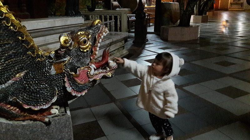Girl and Dragon Sculpture at Doi Suthep temple Young girl reaching out to touch an elaborate dragon sculpture inside a temple at Doi Suthep temple.