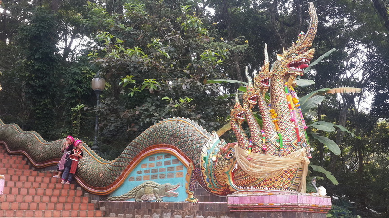 Colorful dragon and alligator sculpture with trees in the background at Wat Phra That Doi Suthep.