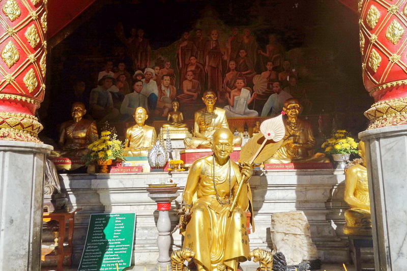 Golden monk statues with mural background inside a temple at Doi Suthep temple.