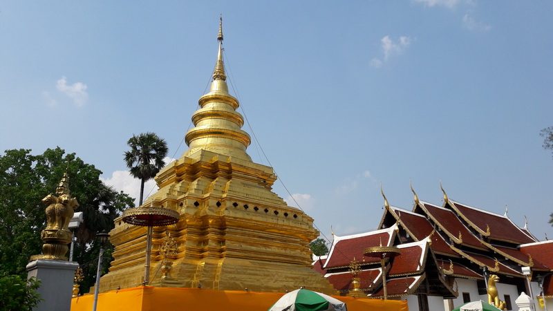 Golden Stupa in Thai Temple at Wat Phra That Si Chom Thong Golden stupa with traditional Thai temple roofs against a blue sky at Wat Phra That Si Chom Thong.