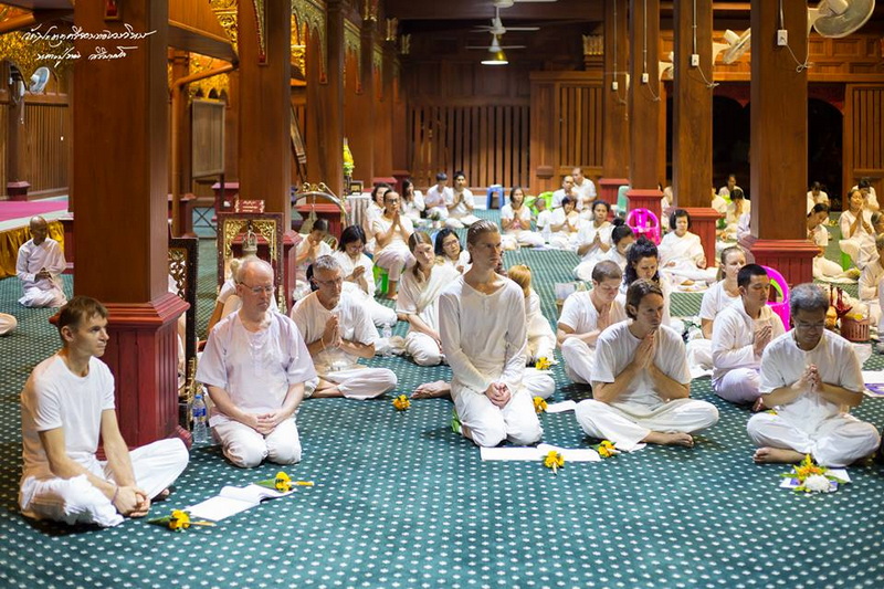 Meditation inside a Wooden Temple at Wat Phra That Sri Chom Thong People meditating in white robes inside a wooden temple with green carpet at Wat Phra That Sri Chom Thong.