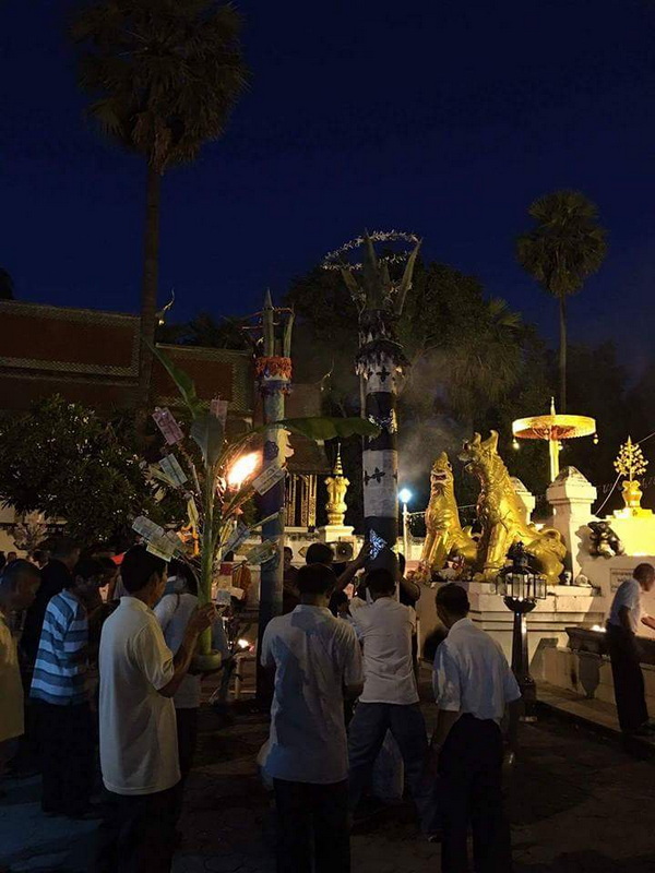 Visitors around golden mythological statues at night in a temple courtyard at Wat Phra That Si Chom Thong.