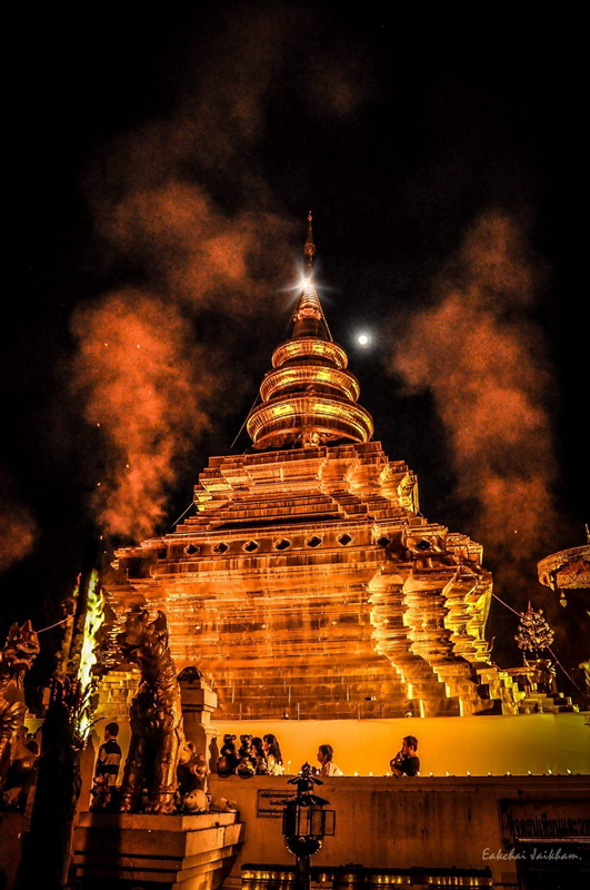 Golden Temple at Night at Wat Phra That Sri Chom Thong Illuminated golden pagoda at night with steam clouds and full moon overhead at Wat Phra That Sri Chom Thong.