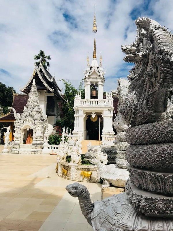 Temple with Serpent Statues and Bell Tower at Wat San Pa Yang Luang White ornate temple structures with serpent statues and detailed carvings at Wat San Pa Yang Luang.