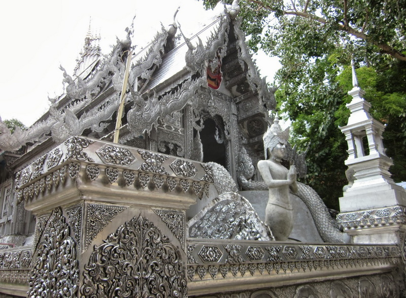 Silver temple with detailed carvings and a deity statue holding a staff at Wat Sri Suphan.