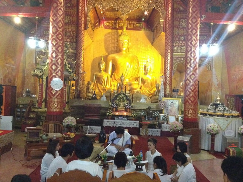 Temple Interior with Buddha Statue at Wat Sri Suphan People sitting in front of a large golden Buddha statue inside a temple at Wat Sri Suphan.