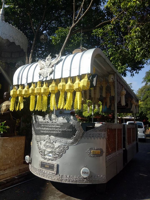 Ornate Tram with Yellow Tassels at Wat Sri Suphan Decorated silver tram with carvings and yellow tassels parked among trees at Wat Sri Suphan.