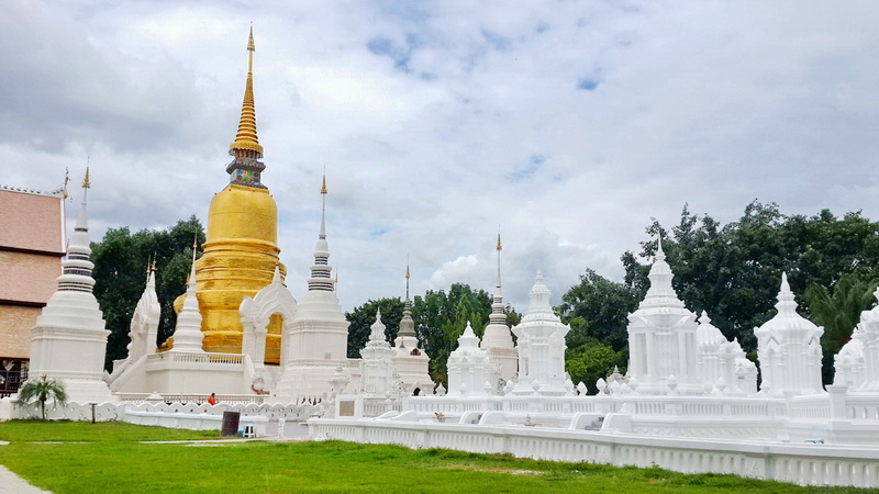 Buddhist Stupa and Temples at Wat Suan Dok White and gold Buddhist stupa with surrounding smaller structures under a cloudy sky at Wat Suan Dok.