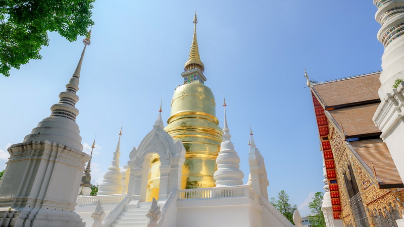 Temple with Golden Spire at Suan Dok Temple White and gold temple with multiple spires against a clear blue sky at Suan Dok Temple.