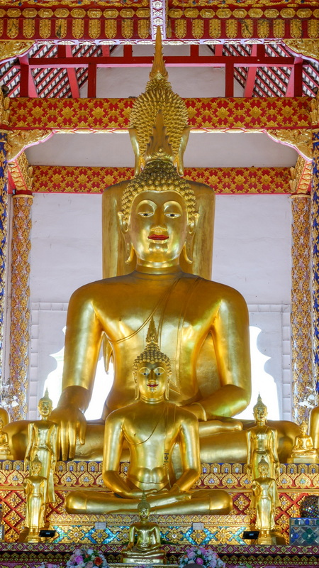 Gold Buddha statues inside a richly decorated temple with detailed accents at Wat Suan Dok.