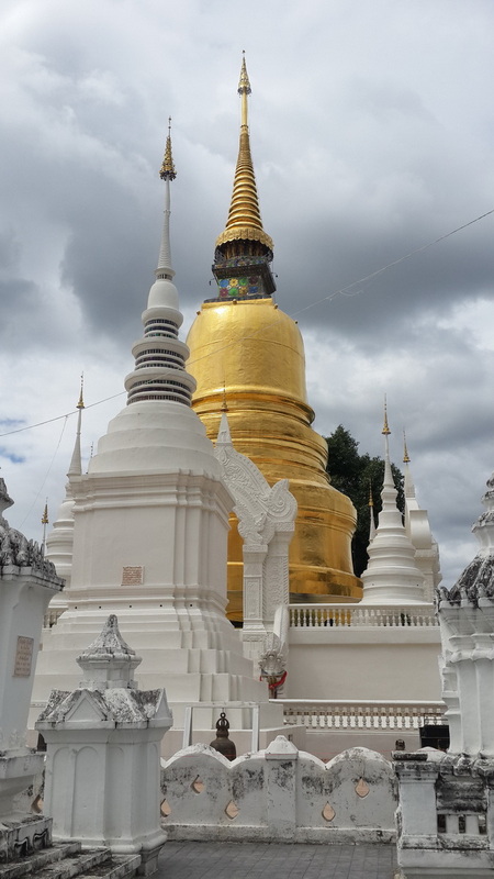 Golden Stupa Scene at Suan Dok Temple A golden stupa with white surrounding stupas under a cloudy sky at Suan Dok Temple.