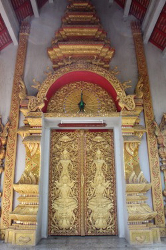 Gold carved doors with detailed patterns and golden architectural decorations at Wat Suan Dok.