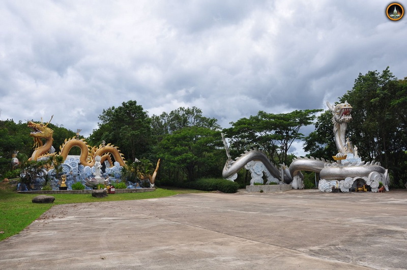 Dragon Statues in Garden at Tha Ton Temple Two dragon statues, gold and silver, on a paved area with trees and clouds behind at Tha Ton Temple.