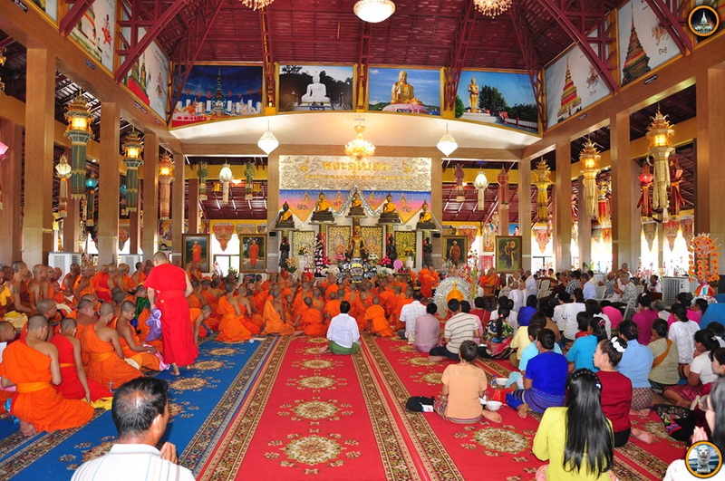 Monks and devotees attending a ceremony inside a colorful temple hall with statues and decorations at Tha Ton Temple.