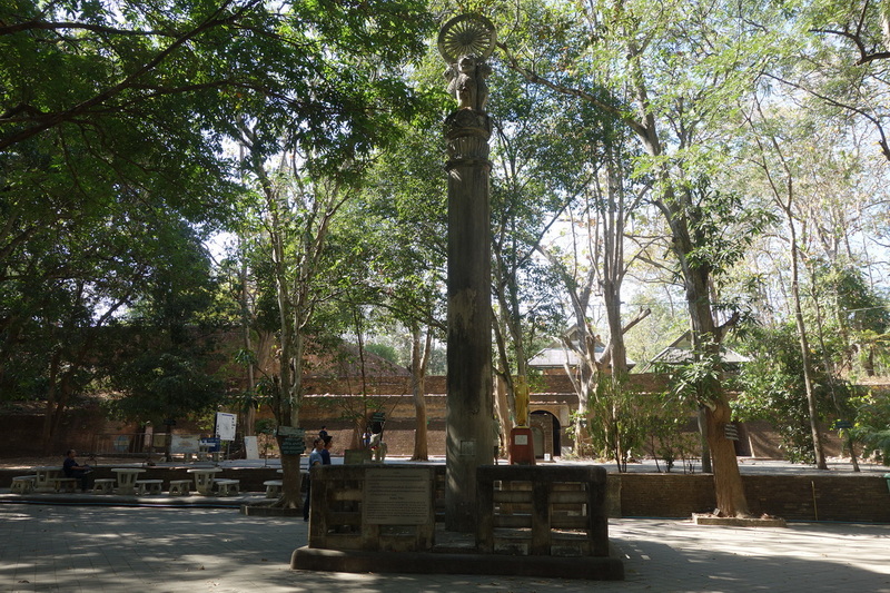 Serene Outdoor Stone Pillar at Wat Umong Stone pillar surrounded by trees and benches in a tranquil outdoor space at Wat Umong.