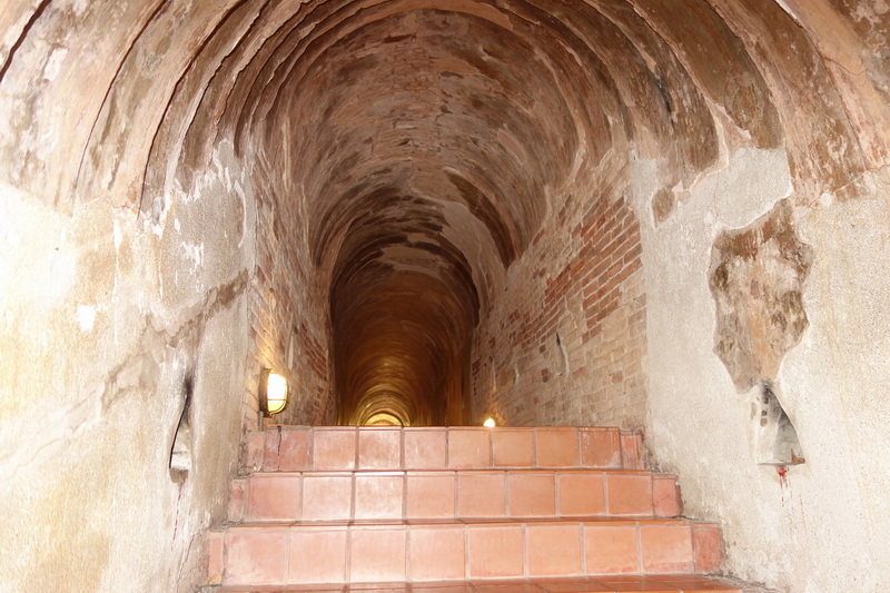 Arched Brick Tunnel Entrance at Wat Umong Brick tunnel with stairs and lighting, leading into a narrow passageway at Wat Umong.