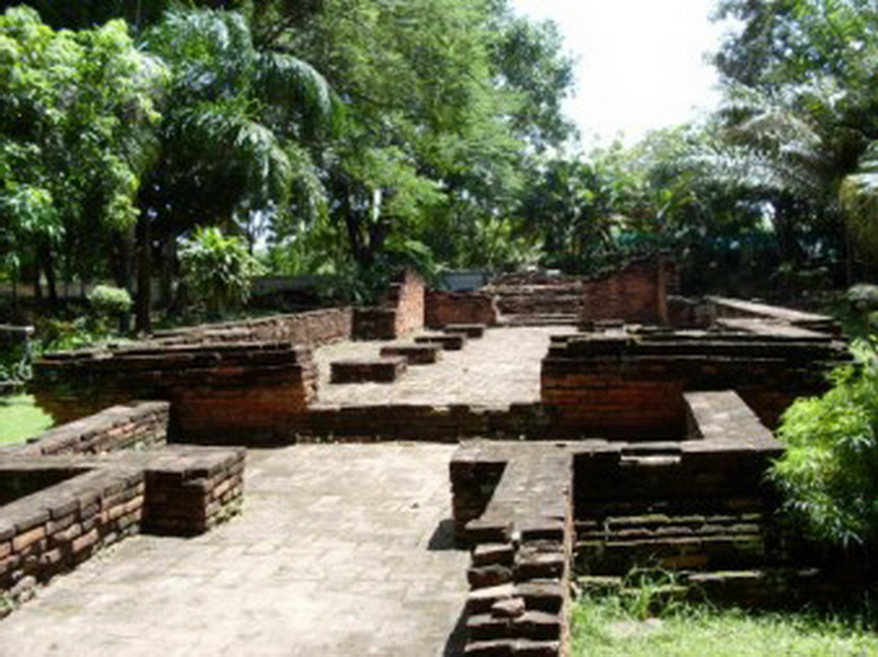 Ancient brick ruins surrounded by lush green trees and foliage at Wiang Kum Kam.