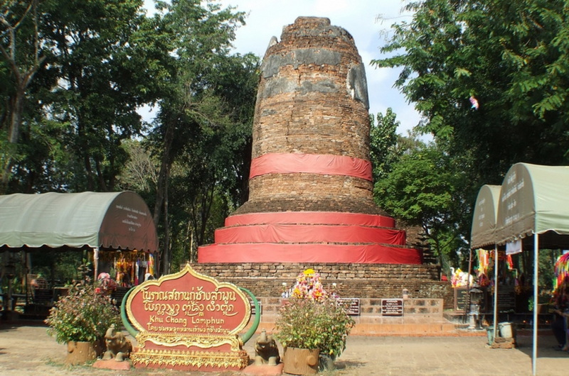 Brick Stupa with Trees and Market at Ku Chang Ku Ma Ancient brick stupa wrapped in red cloth with trees and market stalls nearby at Ku Chang Ku Ma.
