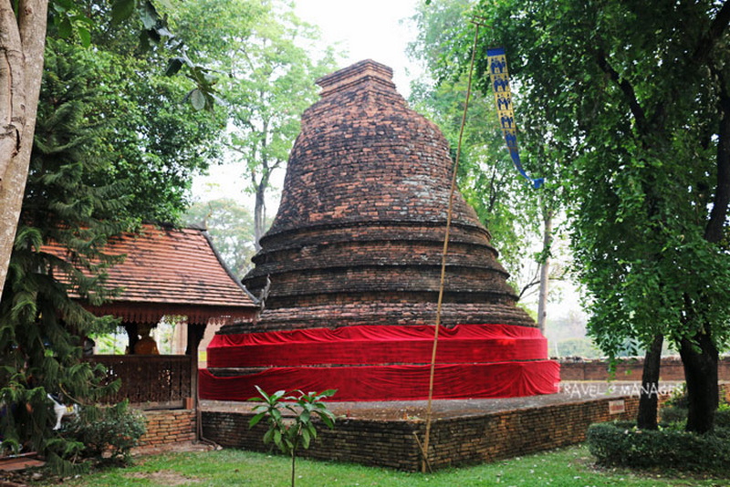 Ancient brick stupa with trees and pavilion around it, covered partly with red cloth at Ku Chang Ku Ma.