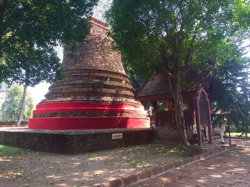 Brick stupa with red cloth, near a wooden pavilion and trees at Ku Chang Ku Ma.