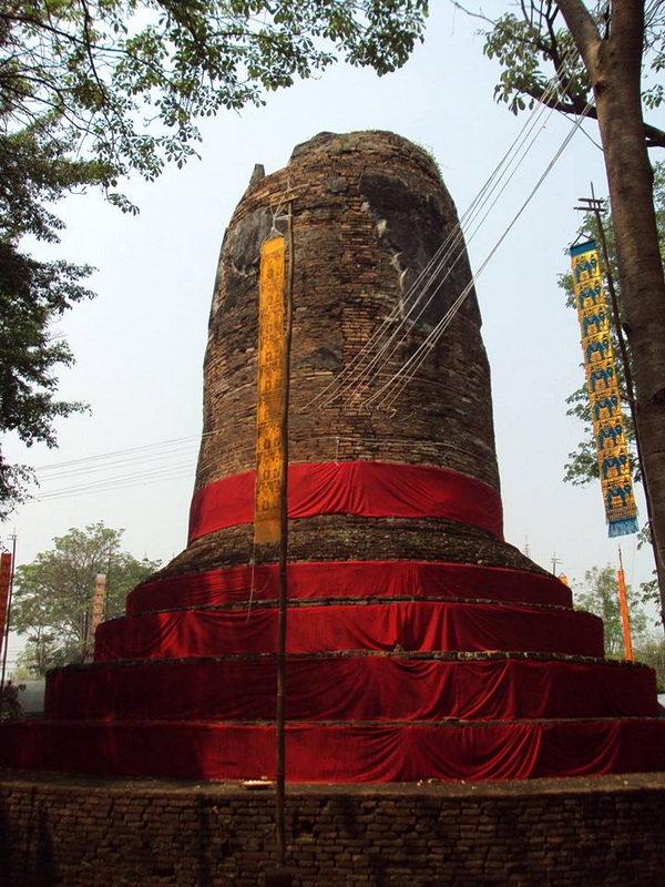 Historic Brick Stupa at Ku Chang Ku Ma Ancient brick stupa covered with red cloth, with trees and wires nearby at Ku Chang Ku Ma.