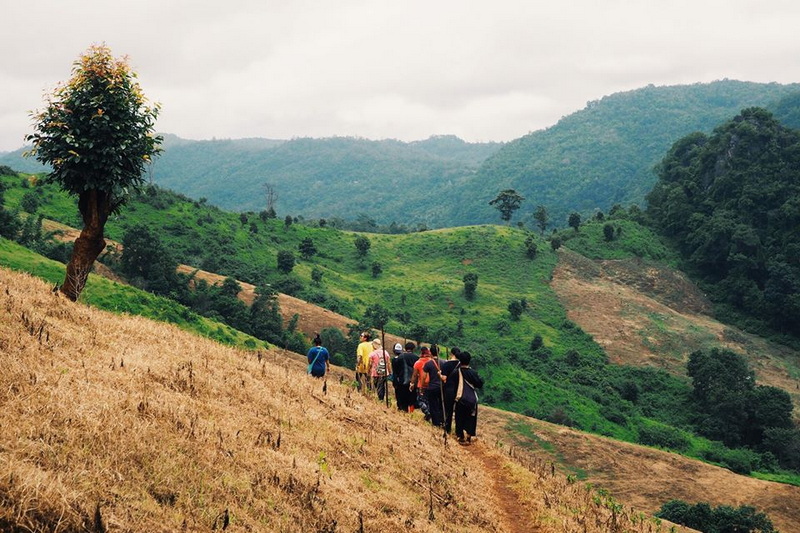 Scenic Hilltop Trail at Ban Ja Boe People walking on a dirt trail through green hills under a cloudy sky at Ban Ja Boe.