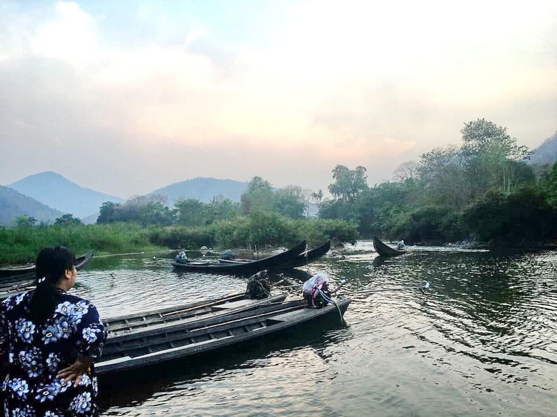 Scenic River and Mountain View at Mae Hong Son Woman watching boats on a river surrounded by trees and mountains at Mae Hong Son.