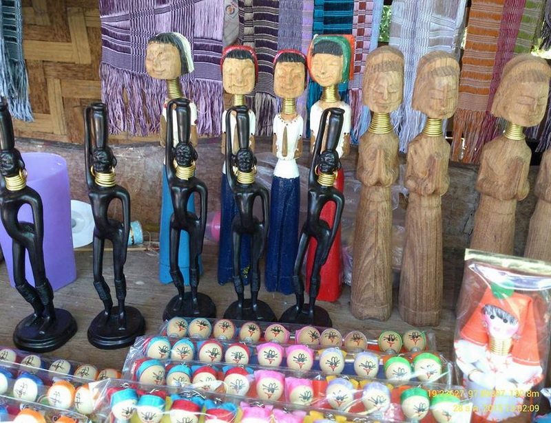 Collection of wooden and painted figurines with fabric backgrounds on display at Ban Nam Phiang Din.