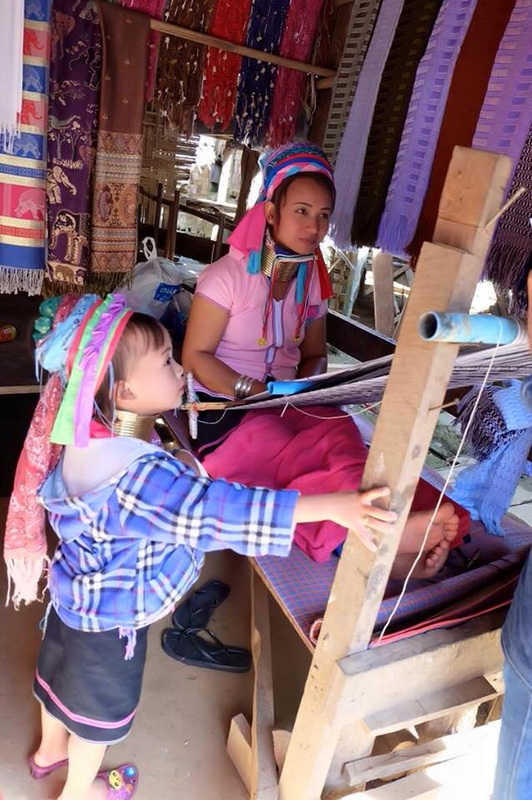 Textile Shop with Fabrics at Ban Nam Phiang Din Woman and girl sitting inside a shop with colorful textiles and a loom at Ban Nam Phiang Din.