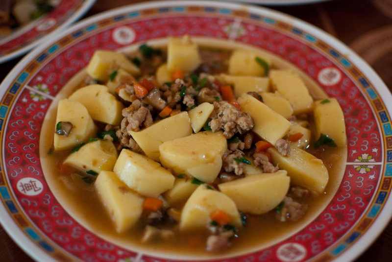 Traditional Potatoes and Meat Dish at Ban Rak Thai Diced potatoes with ground meat and vegetables in a savory broth on a patterned plate at Ban Rak Thai.
