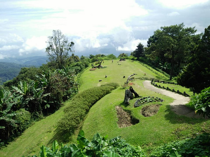 Scenic Hilltop View at Mae Hong Son A green hillside with a winding path surrounded by trees and bushes at Mae Hong Son.
